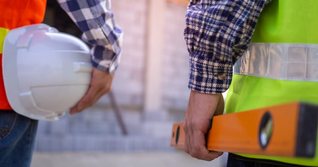 Men holding a level and white hard hat