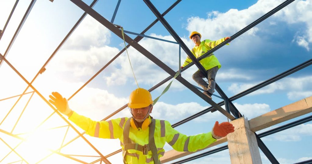 Men in hi vis working at height. One man is in fall position wearing height safety gear