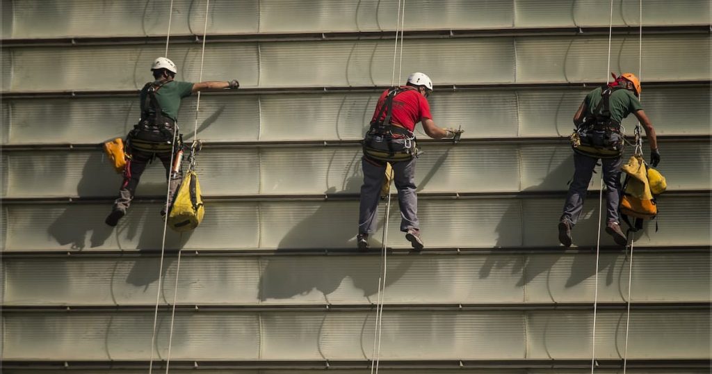 3 males working at height wearing safety harnesses and height safety gear